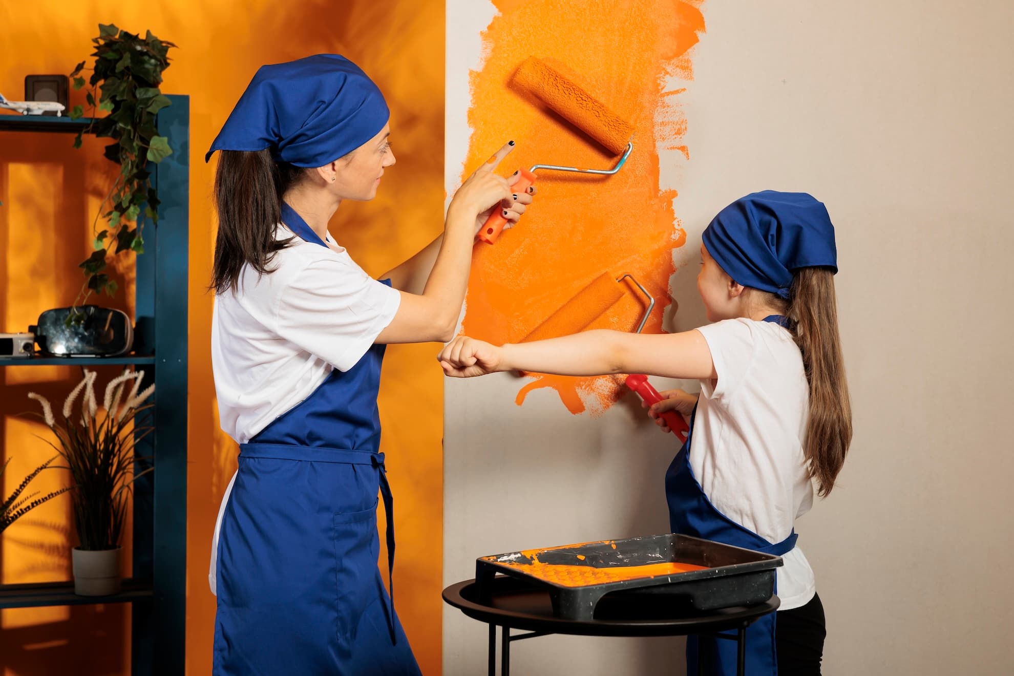 Parent and child painting a room with orange paint